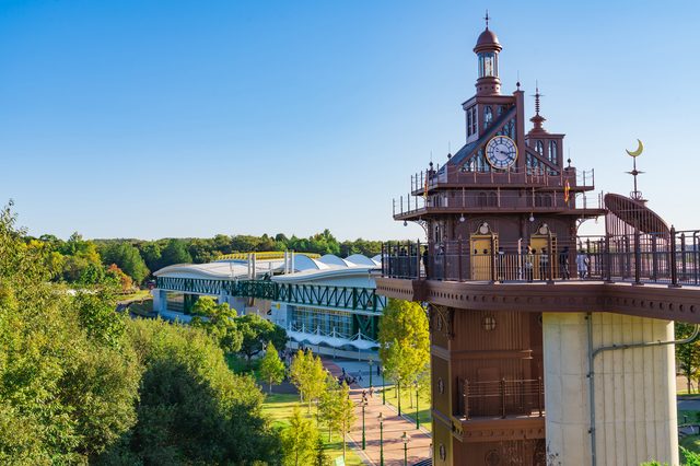 The ornate clock tower at the Hill of Youth, with a glass-roofed building set in green parkland.