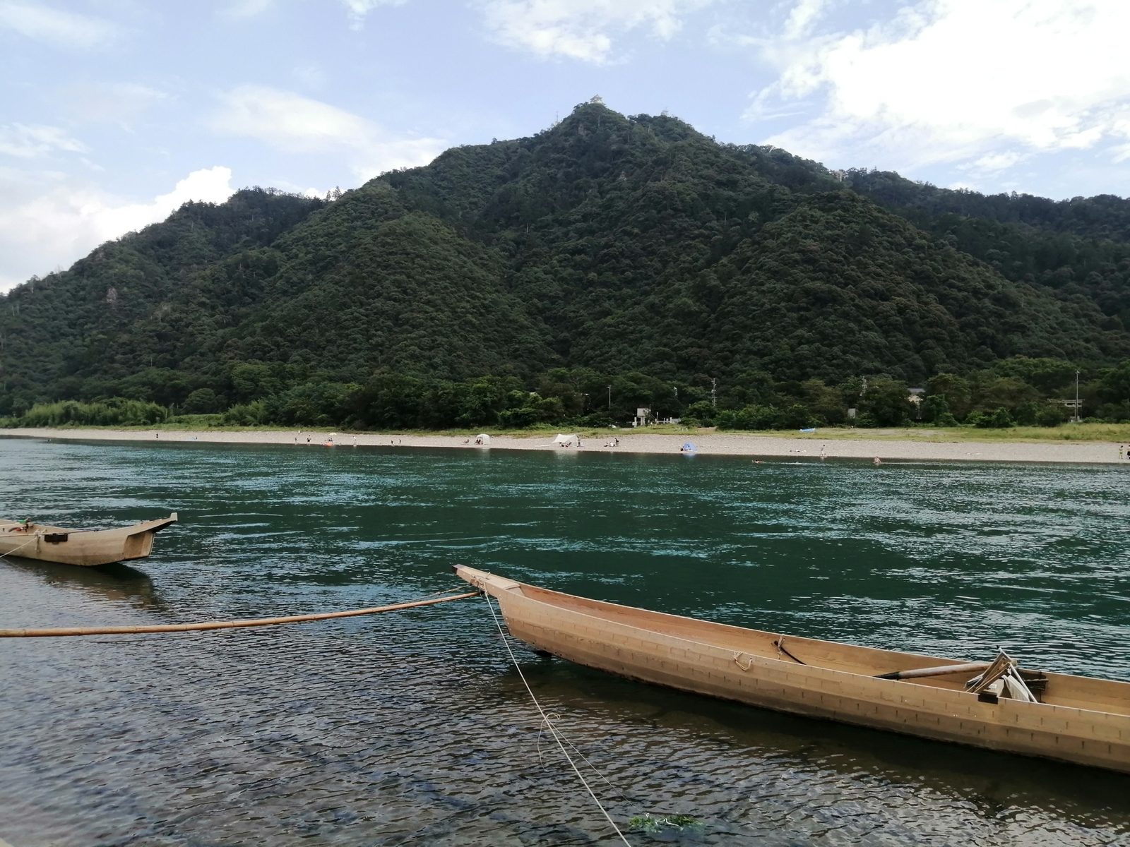 昼の長良川にもやう鵜舟。金華山のふもとを流れ、山頂には小さく岐阜城が見えます。